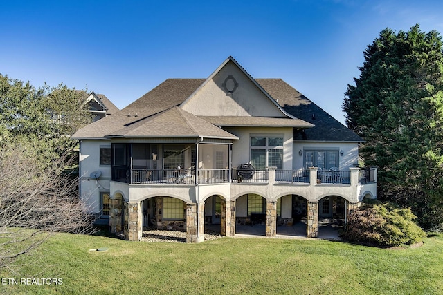 back of house with stucco siding, a lawn, stone siding, a patio, and a sunroom