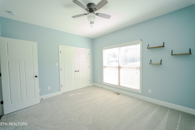 unfurnished bedroom with ceiling fan, a closet, and light colored carpet