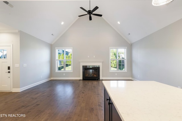 unfurnished living room featuring ceiling fan, dark hardwood / wood-style flooring, high vaulted ceiling, and a wealth of natural light