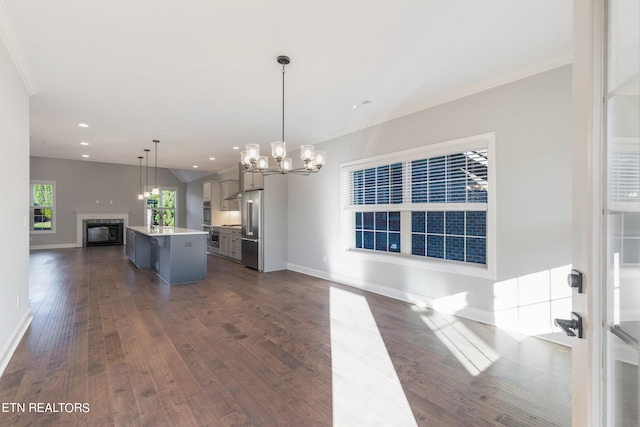 kitchen featuring dark wood-type flooring, stainless steel refrigerator, decorative light fixtures, and a center island