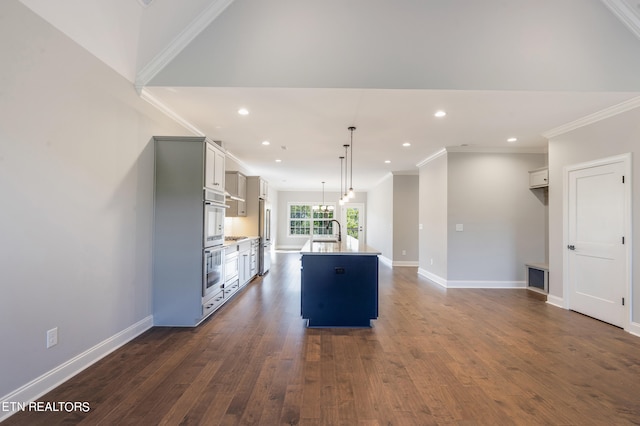kitchen with a sink, a kitchen island with sink, baseboards, ornamental molding, and dark wood-type flooring