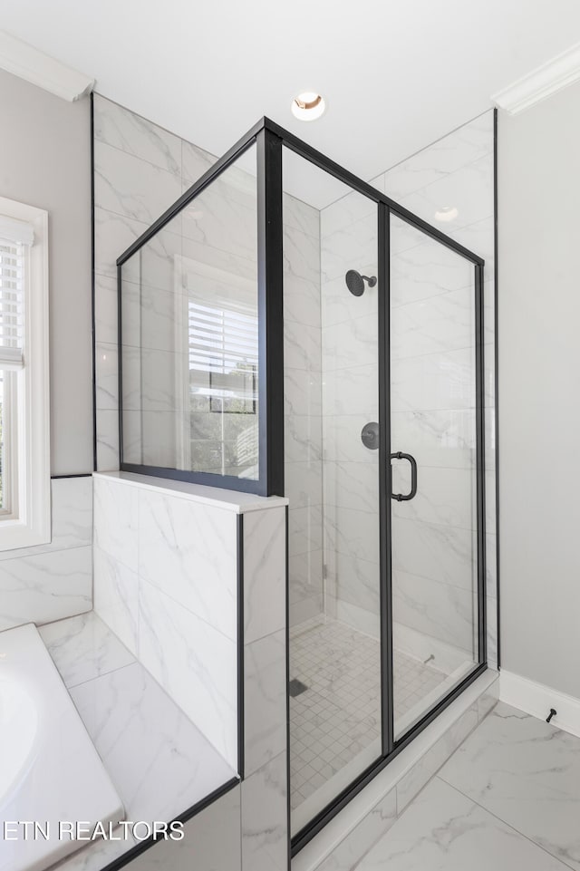 bathroom featuring a healthy amount of sunlight, marble finish floor, a marble finish shower, and a bathtub