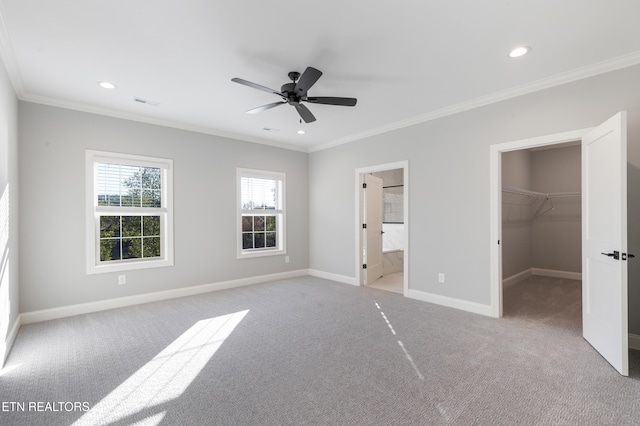 unfurnished bedroom with light carpet, ensuite bath, ceiling fan, and a walk in closet