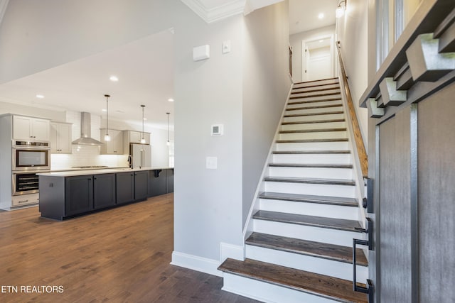 stairs featuring hardwood / wood-style flooring, crown molding, and sink