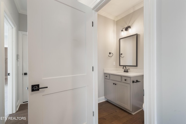 bathroom featuring baseboards, ornamental molding, vanity, and wood finished floors