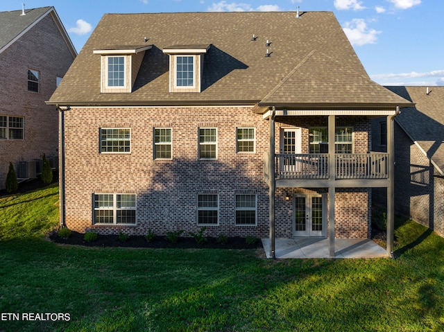rear view of property with a yard, central air condition unit, a patio area, french doors, and brick siding