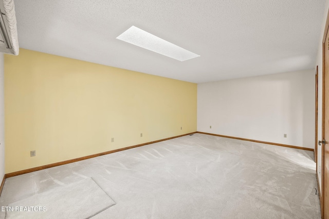 carpeted spare room with a textured ceiling and a skylight