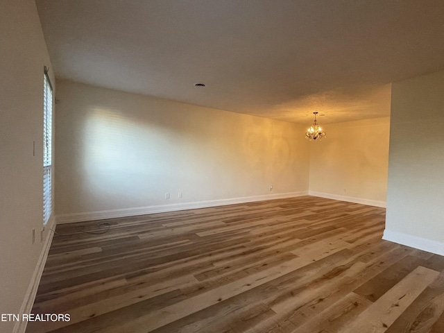 unfurnished room featuring dark wood-type flooring and a notable chandelier