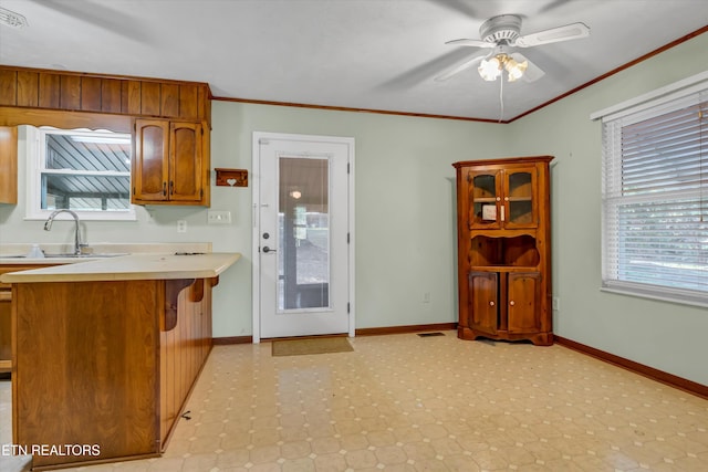 kitchen with kitchen peninsula, a kitchen breakfast bar, ceiling fan, crown molding, and sink