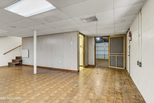 basement featuring a paneled ceiling and parquet flooring