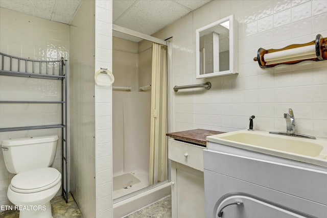 bathroom featuring a drop ceiling, tile walls, and walk in shower