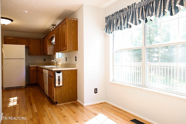 kitchen featuring white appliances, sink, light hardwood / wood-style floors, and a textured ceiling