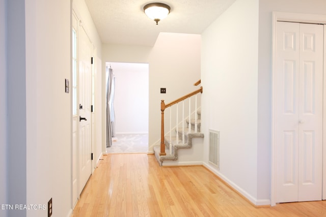 entryway with light hardwood / wood-style floors and a textured ceiling