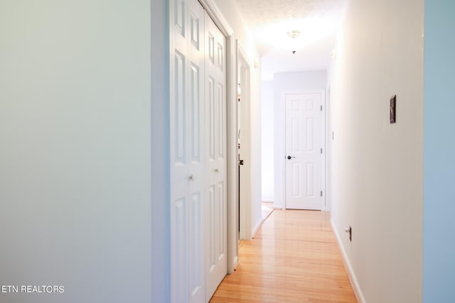 hall featuring a textured ceiling and light hardwood / wood-style flooring