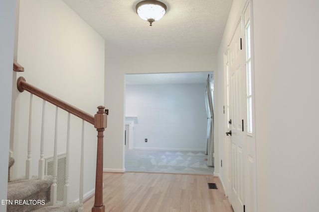 hallway featuring light hardwood / wood-style flooring and a textured ceiling