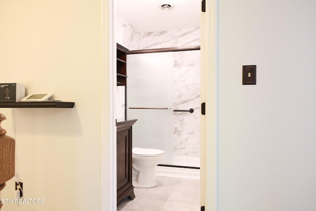 bathroom with tile patterned floors, a shower with shower door, vanity, and toilet