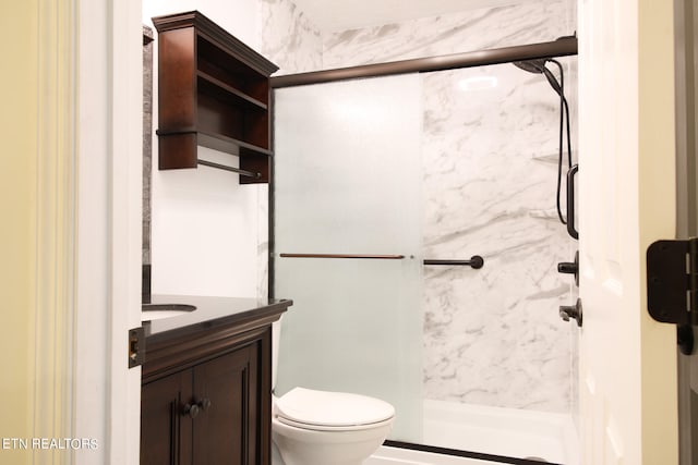 bathroom featuring a shower with door, vanity, and toilet