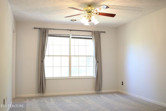 spare room featuring a textured ceiling, ceiling fan, and light colored carpet