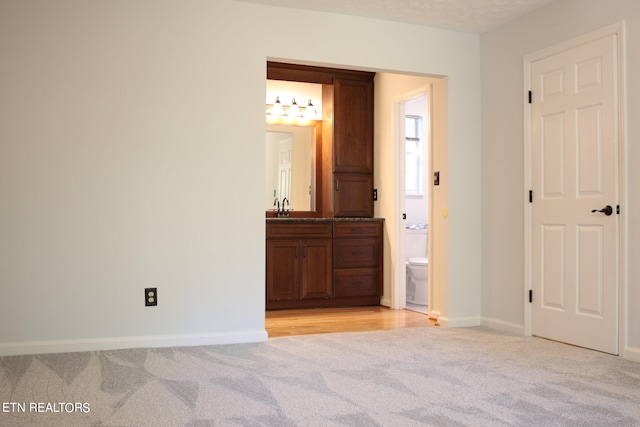 unfurnished room with a textured ceiling, sink, and light colored carpet