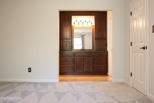 corridor featuring light carpet and sink