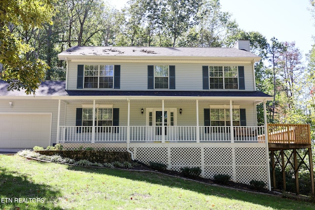 view of front of home featuring a garage, a front yard, and covered porch