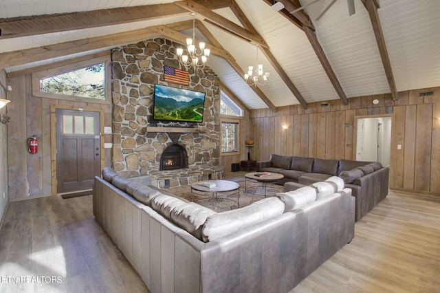 living area featuring light wood-style floors, an inviting chandelier, a fireplace, wooden walls, and beam ceiling