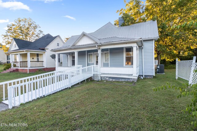 bungalow-style home with a porch, metal roof, and a front yard