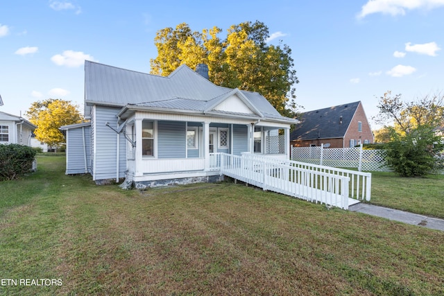 bungalow with fence, a front lawn, a chimney, covered porch, and metal roof