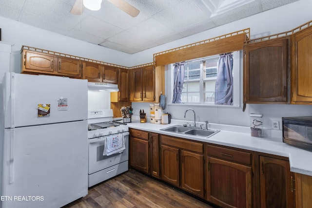 kitchen featuring white appliances, ceiling fan, light countertops, under cabinet range hood, and a sink