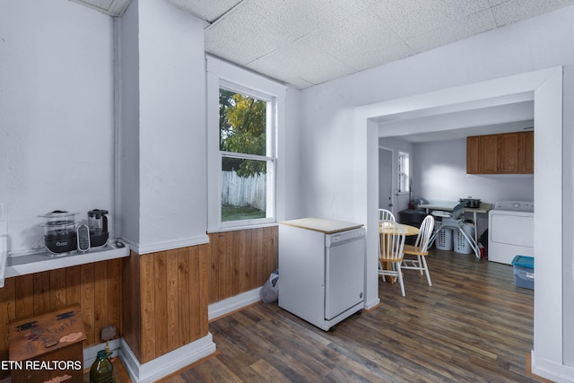 kitchen with washer / dryer, a drop ceiling, dark wood-type flooring, white refrigerator, and wood walls