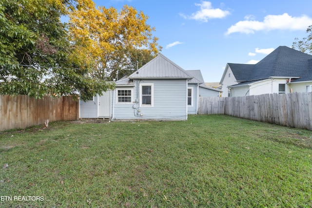 back of property with a yard and a fenced backyard