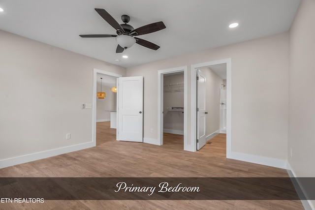 unfurnished bedroom featuring a spacious closet, ceiling fan, a closet, and light hardwood / wood-style flooring