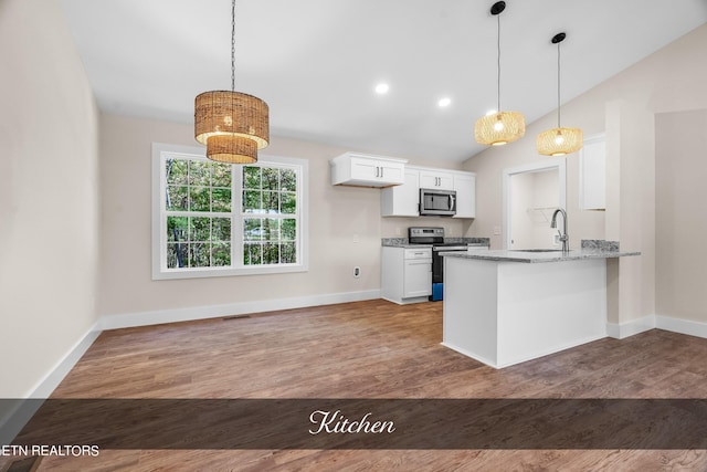 kitchen with light stone countertops, hardwood / wood-style floors, kitchen peninsula, white cabinetry, and appliances with stainless steel finishes