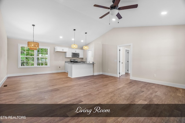 kitchen with lofted ceiling, hanging light fixtures, light hardwood / wood-style floors, and white cabinets