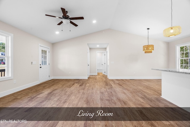 unfurnished living room featuring ceiling fan, vaulted ceiling, light hardwood / wood-style floors, and a wealth of natural light