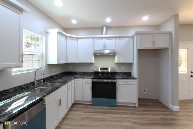 kitchen featuring stainless steel appliances, dark stone countertops, sink, white cabinets, and light hardwood / wood-style floors