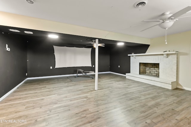 basement featuring a fireplace, wood-type flooring, and ceiling fan