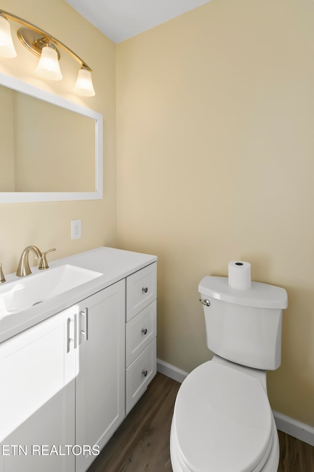 bathroom with toilet, vanity, and wood-type flooring