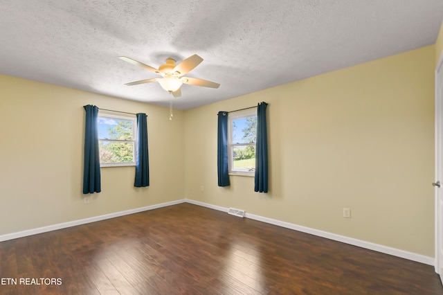 empty room with ceiling fan, a textured ceiling, and dark wood-type flooring