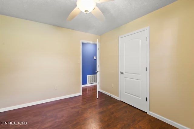 spare room featuring dark hardwood / wood-style floors, a textured ceiling, and ceiling fan