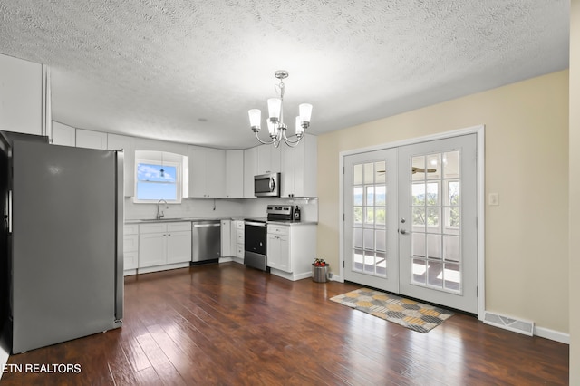 kitchen featuring pendant lighting, sink, white cabinetry, appliances with stainless steel finishes, and dark hardwood / wood-style floors