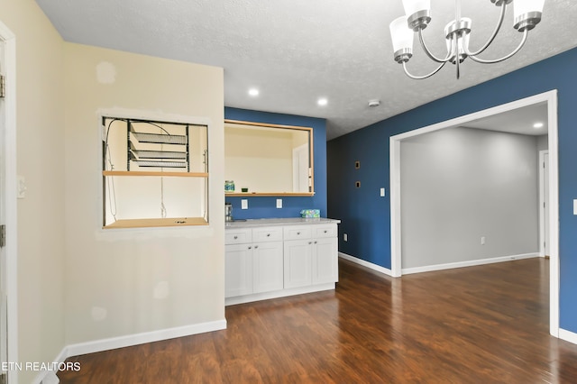 kitchen featuring a textured ceiling, white cabinetry, decorative light fixtures, and dark hardwood / wood-style flooring