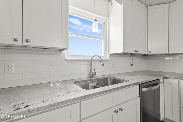 kitchen featuring tasteful backsplash, sink, dishwasher, hanging light fixtures, and white cabinetry