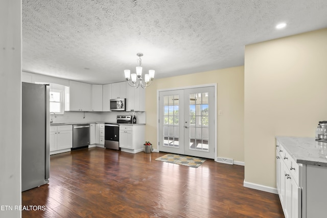 kitchen featuring hanging light fixtures, white cabinets, appliances with stainless steel finishes, and a wealth of natural light