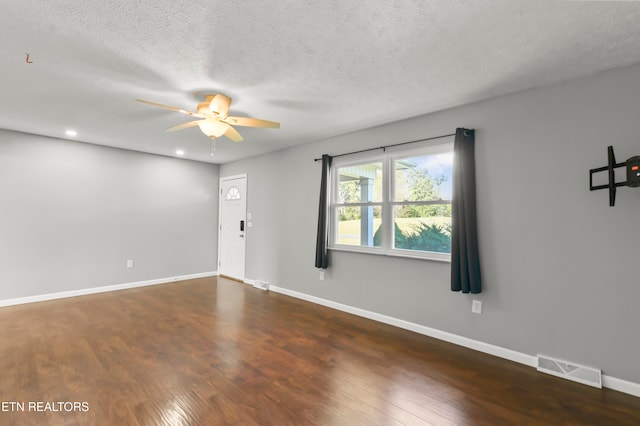 spare room with ceiling fan, a textured ceiling, and dark hardwood / wood-style floors