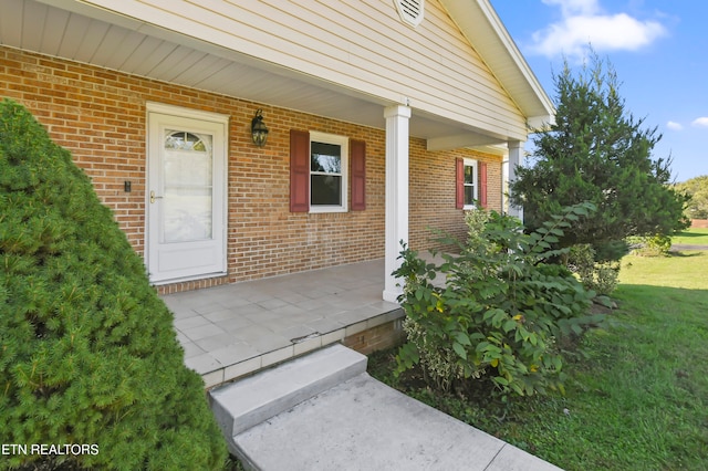 property entrance featuring a lawn and covered porch