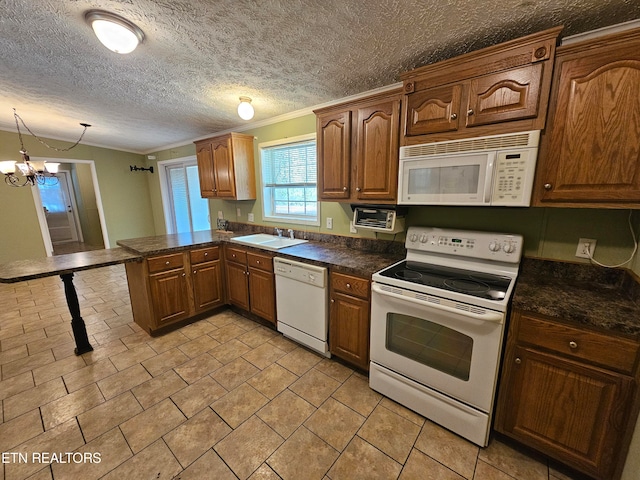 kitchen featuring sink, decorative light fixtures, ornamental molding, kitchen peninsula, and white appliances