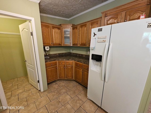 kitchen featuring crown molding, white fridge with ice dispenser, light tile patterned floors, and a textured ceiling