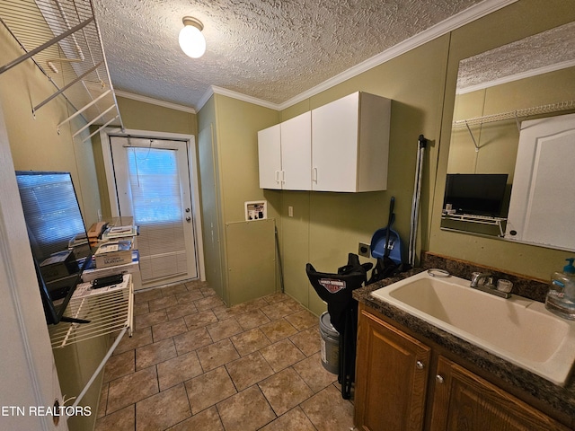 kitchen featuring light tile patterned flooring, sink, white cabinetry, crown molding, and a textured ceiling