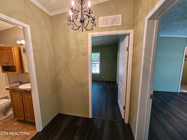 corridor featuring dark wood-type flooring, ornamental molding, and a textured ceiling